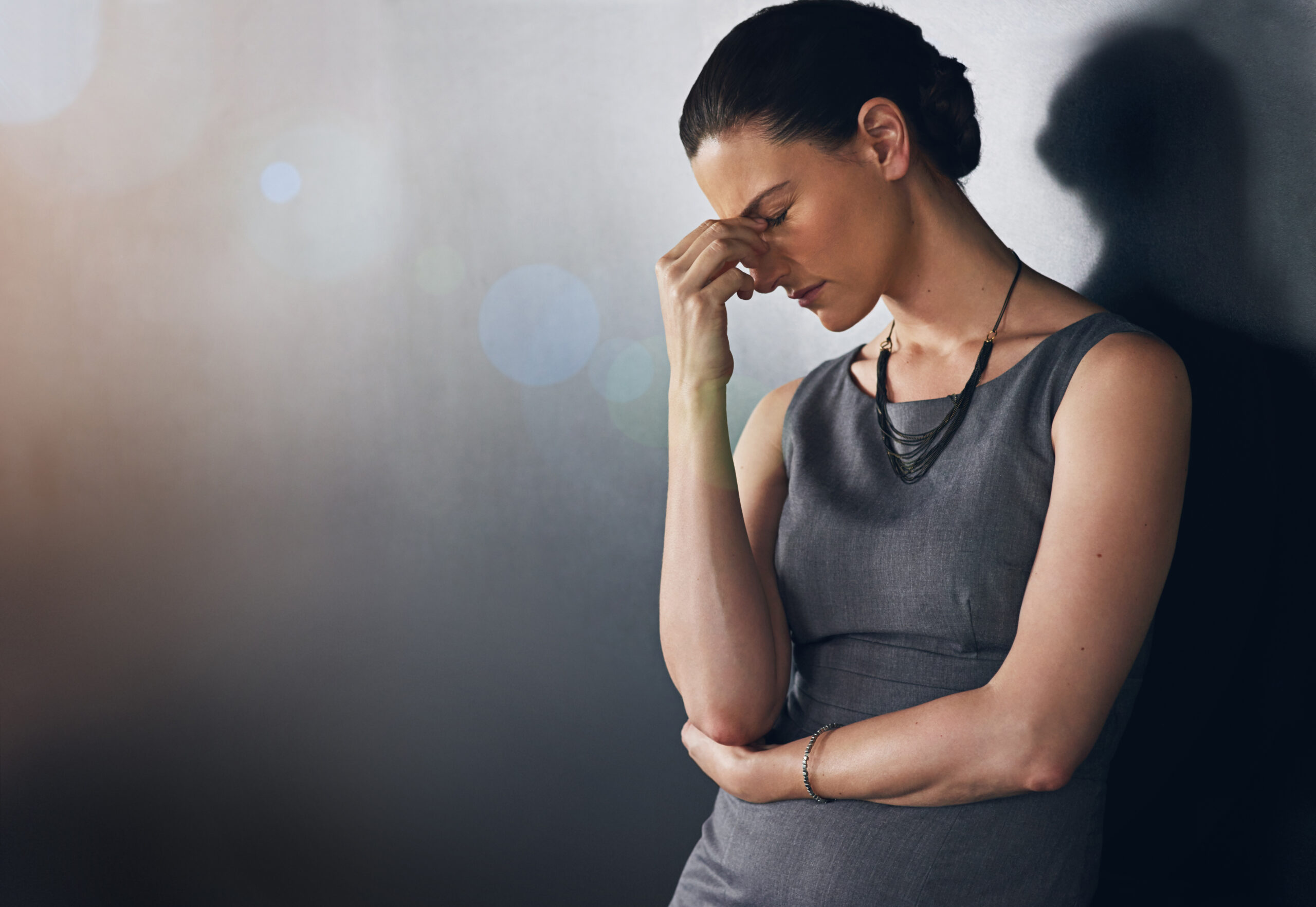 Studio shot of a businesswoman looking stressed out against a grey background.